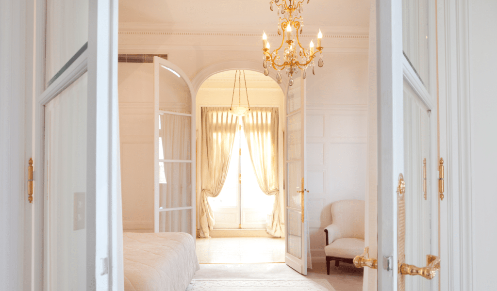 Bedroom viewed through open doors with chandelier