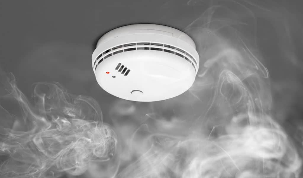 Single smoke alarm on the ceiling surrounded by smoke